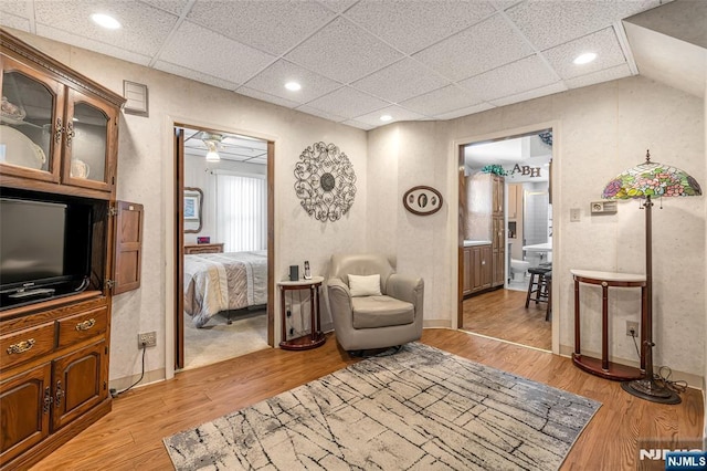 sitting room with recessed lighting, a drop ceiling, light wood-style flooring, and baseboards