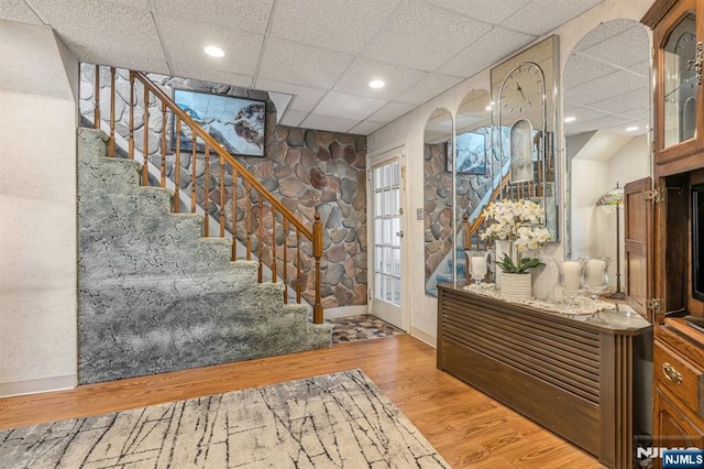 entrance foyer with recessed lighting, a drop ceiling, stairway, and wood finished floors