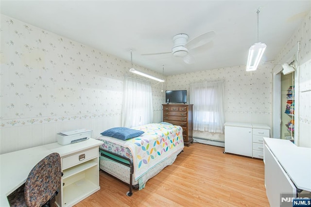 bedroom with a baseboard heating unit, light wood-type flooring, ceiling fan, and wallpapered walls