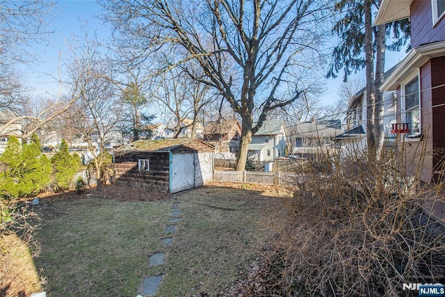 view of yard featuring an outbuilding, a shed, fence, and a residential view