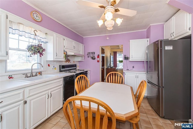 kitchen with black dishwasher, freestanding refrigerator, white cabinets, a sink, and a healthy amount of sunlight