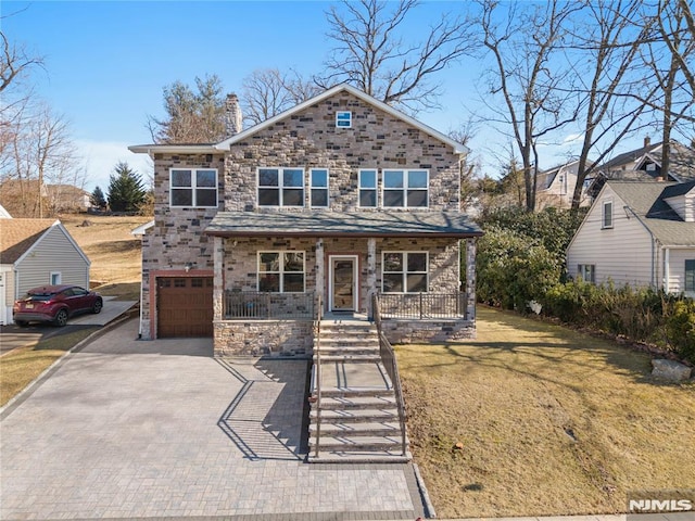 view of front of property with a porch, a garage, decorative driveway, a front lawn, and a chimney