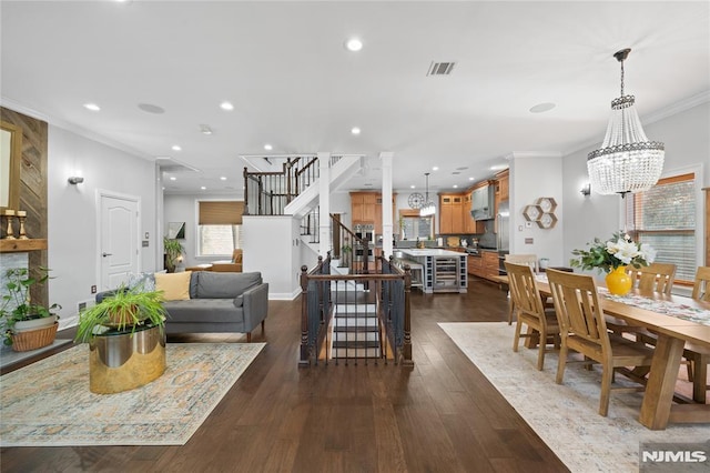 interior space with visible vents, ornamental molding, dark wood-type flooring, a chandelier, and stairs