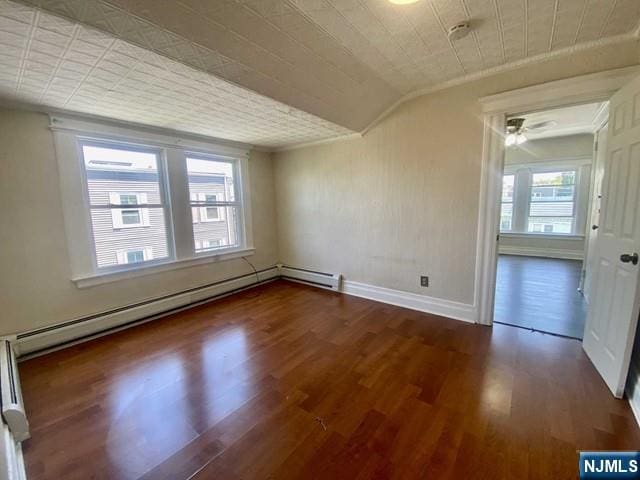 unfurnished room with lofted ceiling, baseboard heating, wood finished floors, and baseboards