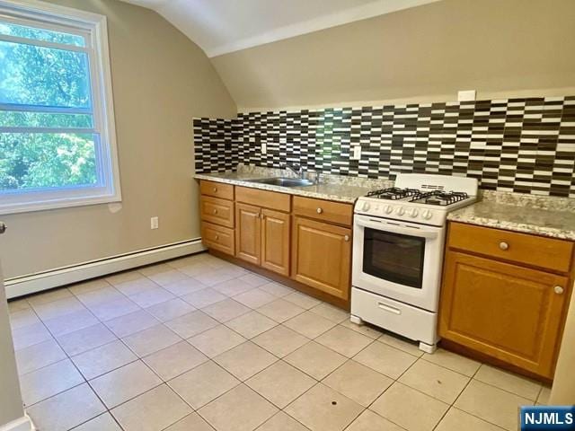 kitchen featuring white gas stove, lofted ceiling, backsplash, a baseboard heating unit, and a sink