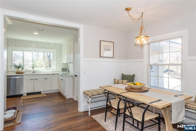 dining space with a wainscoted wall, dark wood-style flooring, breakfast area, and visible vents