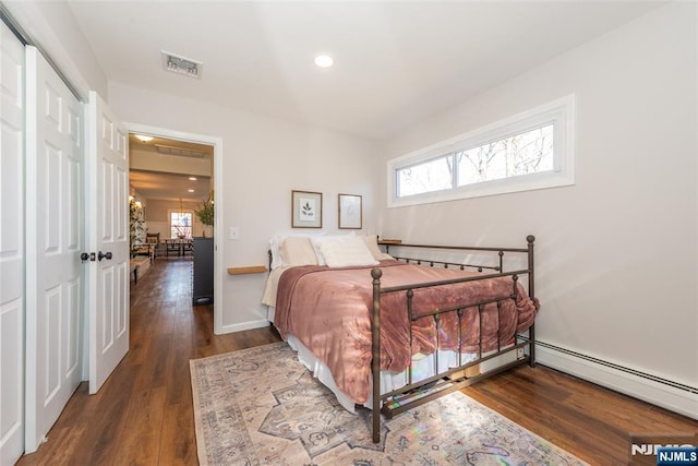 bedroom with a baseboard radiator, recessed lighting, visible vents, wood finished floors, and baseboards