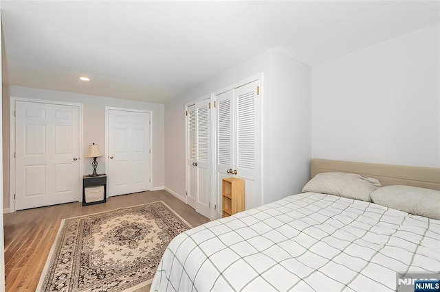 bedroom with light wood-type flooring, baseboards, two closets, and recessed lighting