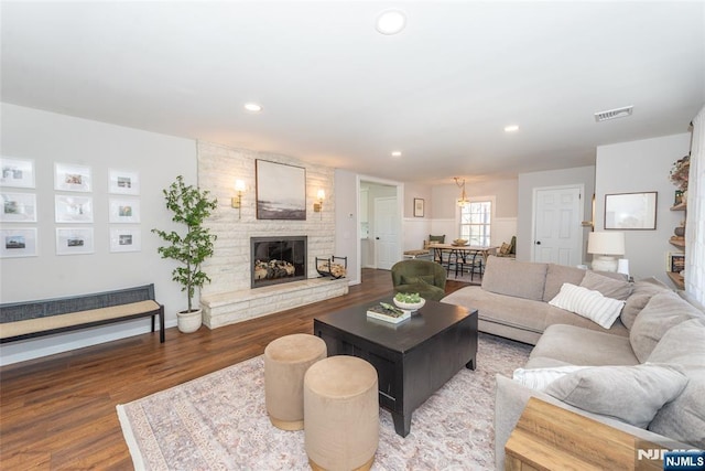 living area with a large fireplace, wood finished floors, visible vents, and recessed lighting