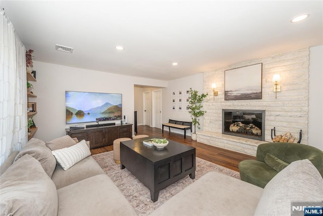 living area featuring recessed lighting, a large fireplace, visible vents, and wood finished floors