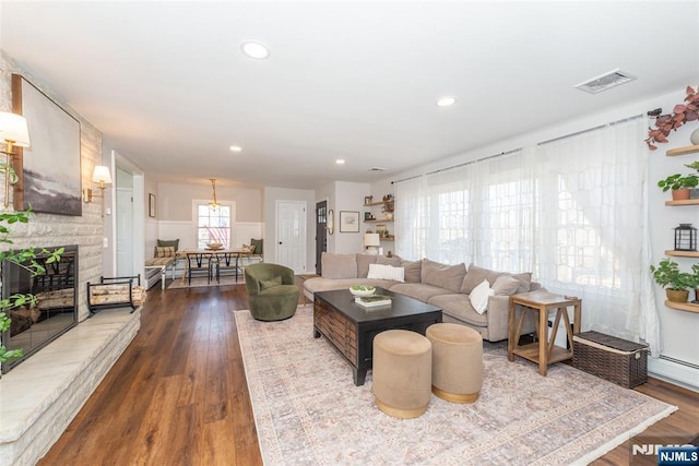 living area with a wealth of natural light, a fireplace, visible vents, and dark wood-style flooring