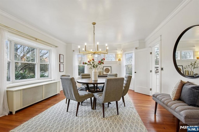 dining space featuring radiator, crown molding, a chandelier, and wood finished floors