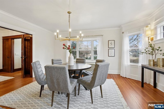 dining room with baseboards, crown molding, an inviting chandelier, and wood finished floors