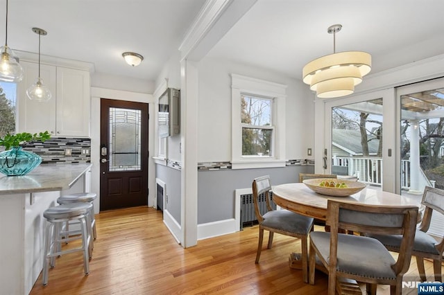 dining space featuring radiator, baseboards, and light wood finished floors