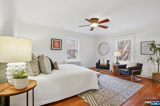 bedroom with baseboards, ceiling fan, wood finished floors, and crown molding