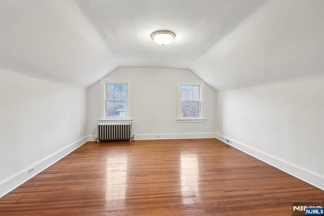 bonus room featuring visible vents, baseboards, lofted ceiling, radiator heating unit, and wood finished floors