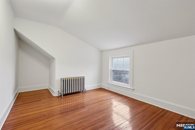 bonus room with radiator, light wood-style flooring, baseboards, and lofted ceiling