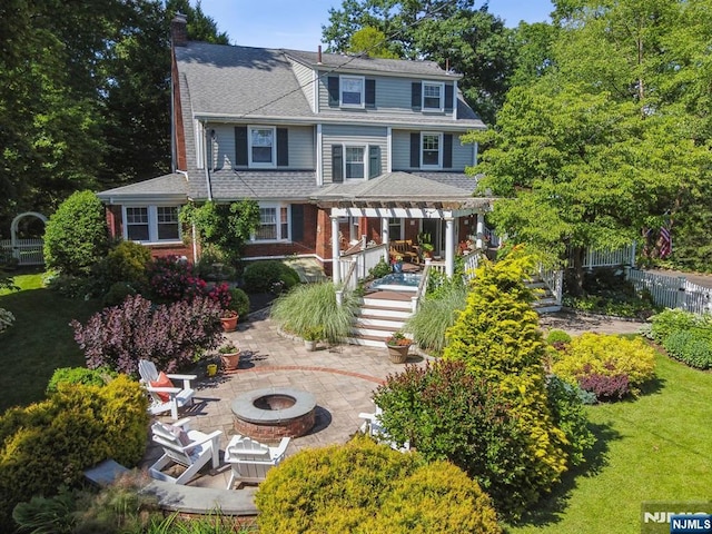 view of front of house with an outdoor fire pit, fence, stairway, a front lawn, and a patio area