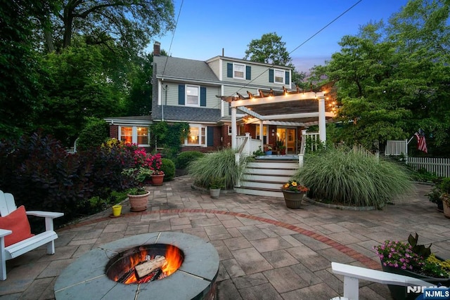 rear view of house with a fire pit, a patio area, fence, and a pergola