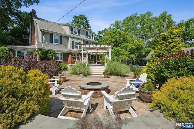 back of property with a fire pit, a patio, a chimney, and a pergola