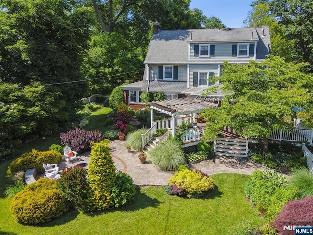 rear view of property with a yard, a chimney, a patio area, and a pergola