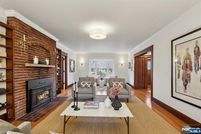 living room featuring ornamental molding, a brick fireplace, wood finished floors, and baseboards