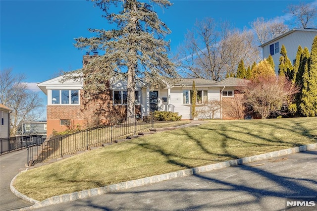 ranch-style house featuring brick siding, fence, a chimney, and a front lawn