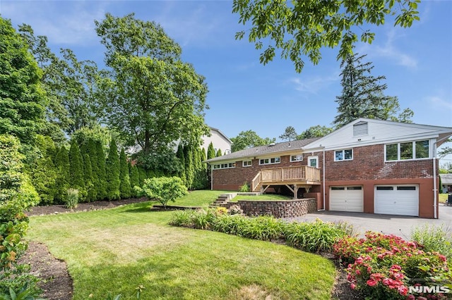 view of yard with a garage, a deck, stairway, and aphalt driveway