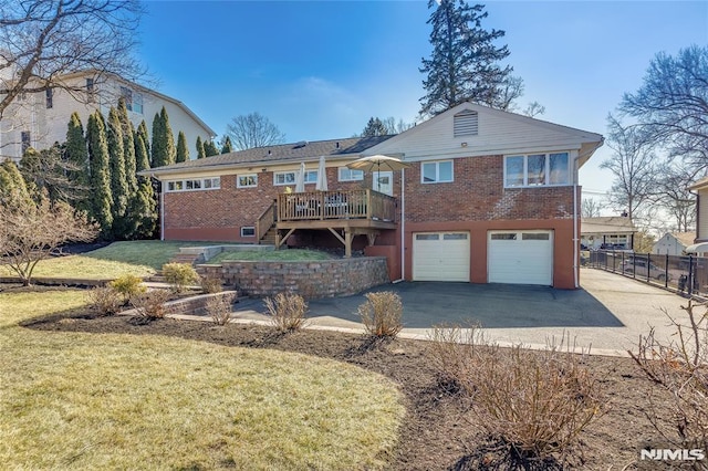 back of property with brick siding, stairway, an attached garage, fence, and driveway