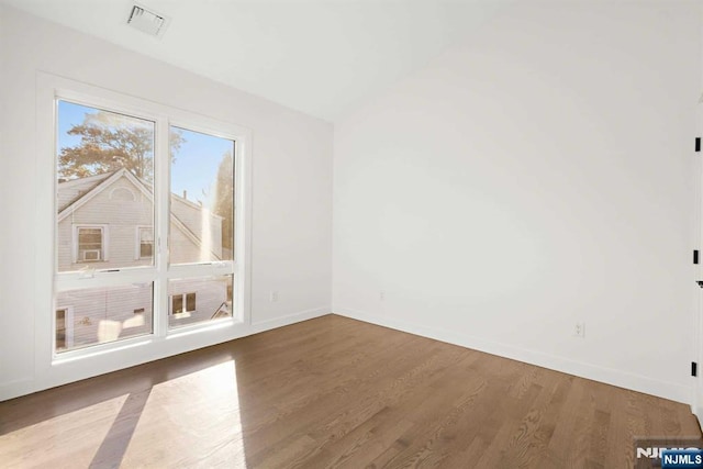 empty room featuring visible vents, baseboards, and wood finished floors