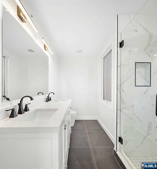 bathroom featuring baseboards, a sink, a marble finish shower, and double vanity