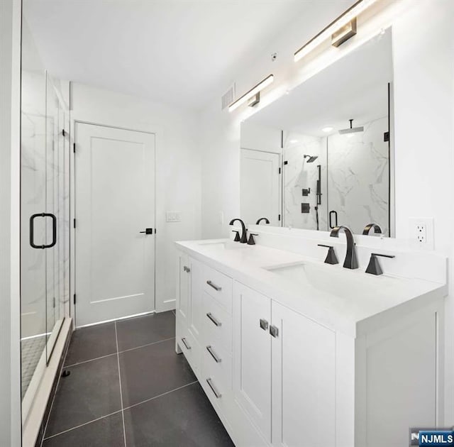 bathroom featuring double vanity, a marble finish shower, and a sink