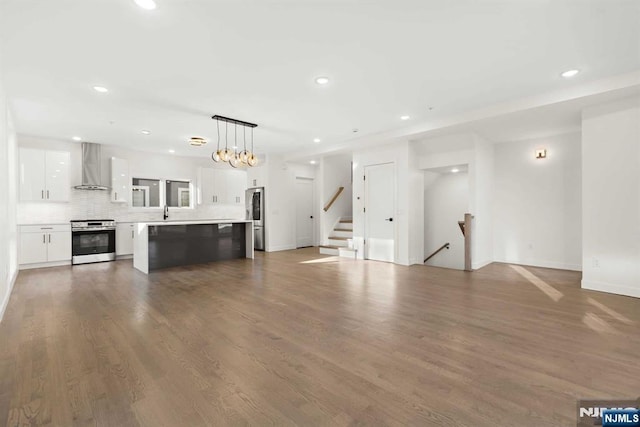 unfurnished living room featuring stairway, wood finished floors, and recessed lighting