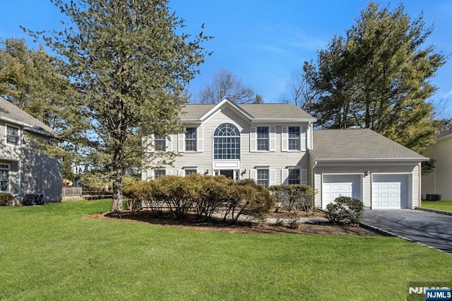 colonial inspired home featuring driveway, a shingled roof, central AC unit, an attached garage, and a front yard