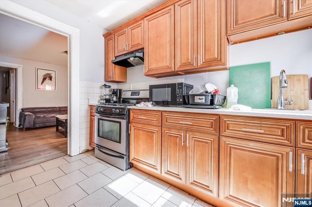 kitchen featuring light countertops, black microwave, stainless steel range with gas stovetop, and under cabinet range hood