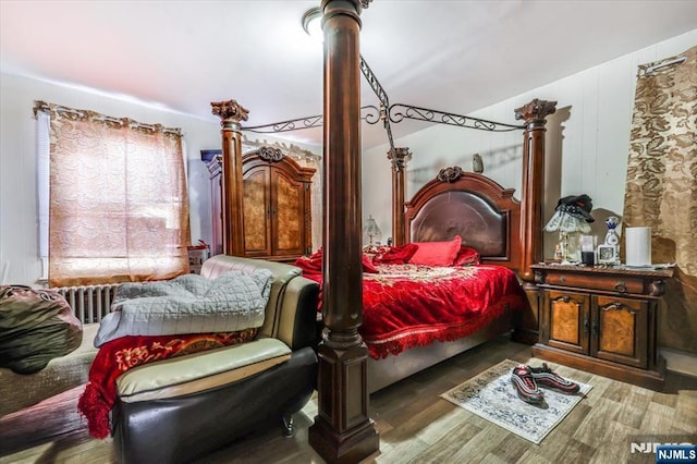 bedroom with ornate columns and wood finished floors