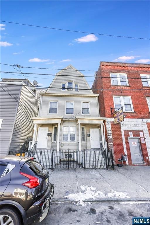 townhome / multi-family property featuring a fenced front yard and a gambrel roof