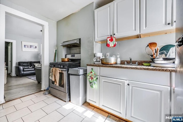 kitchen with under cabinet range hood, white cabinets, a sink, and stainless steel gas range oven