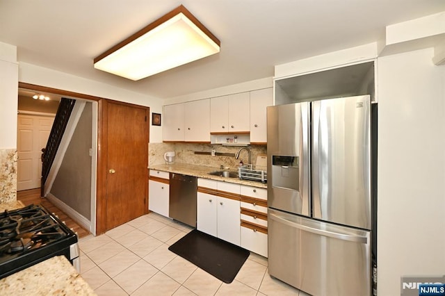 kitchen featuring stainless steel appliances, white cabinets, a sink, and tasteful backsplash