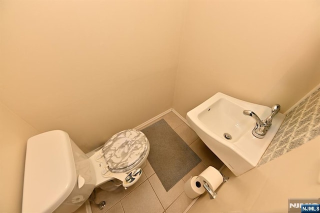 bathroom featuring baseboards, a sink, toilet, and tile patterned floors