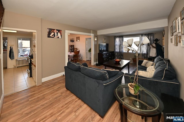 living area featuring light wood finished floors, radiator heating unit, plenty of natural light, and baseboards