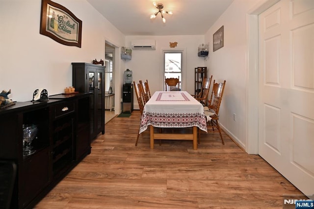 dining room with a wall unit AC, light wood-style flooring, and baseboards