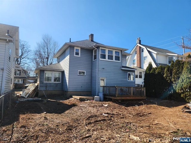 rear view of property with roof with shingles, a chimney, and a wooden deck