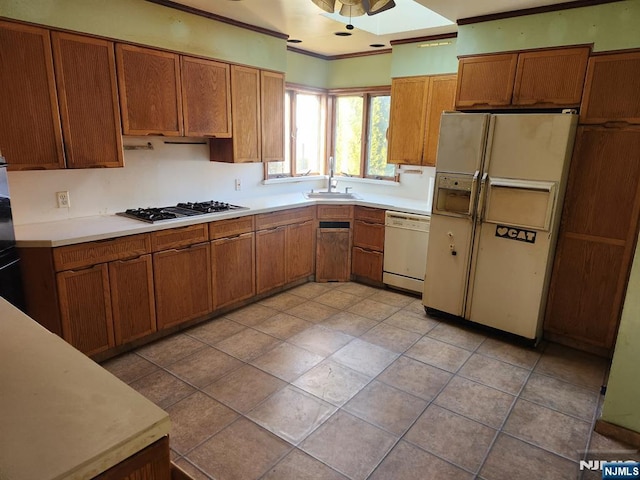 kitchen featuring brown cabinetry, white appliances, and a sink