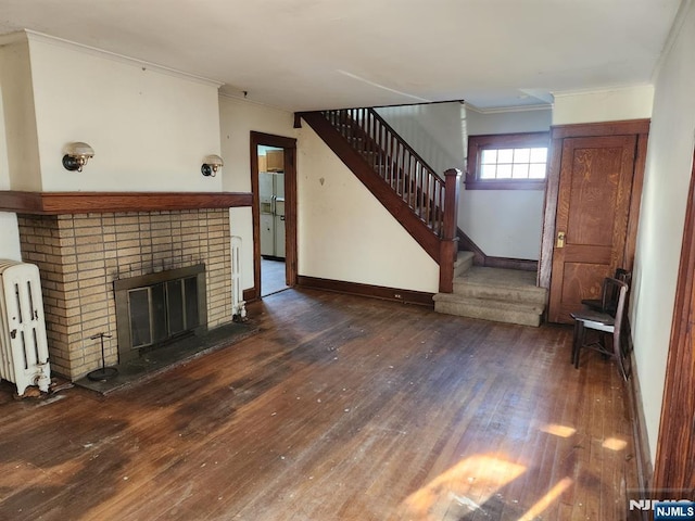 unfurnished living room featuring radiator, wood-type flooring, stairway, crown molding, and a fireplace