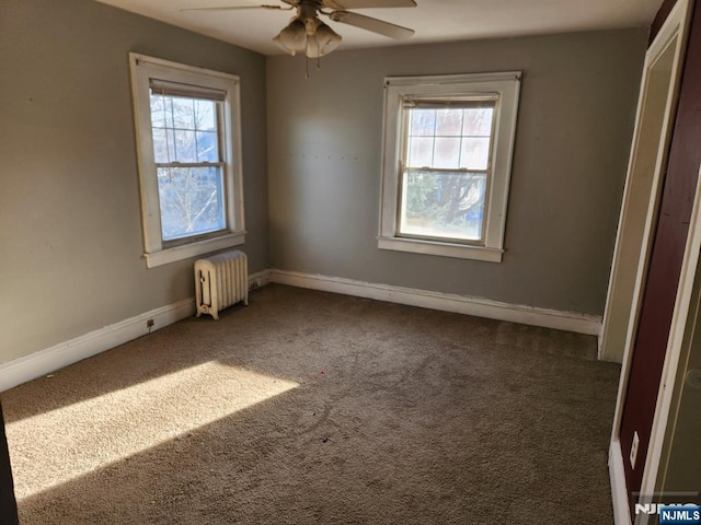 unfurnished bedroom with radiator, carpet, multiple windows, and baseboards