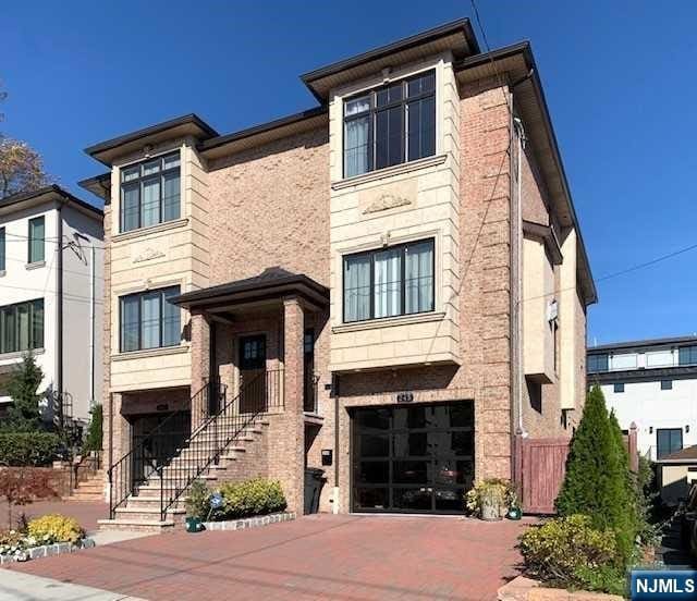 view of front of property with decorative driveway, brick siding, and an attached garage