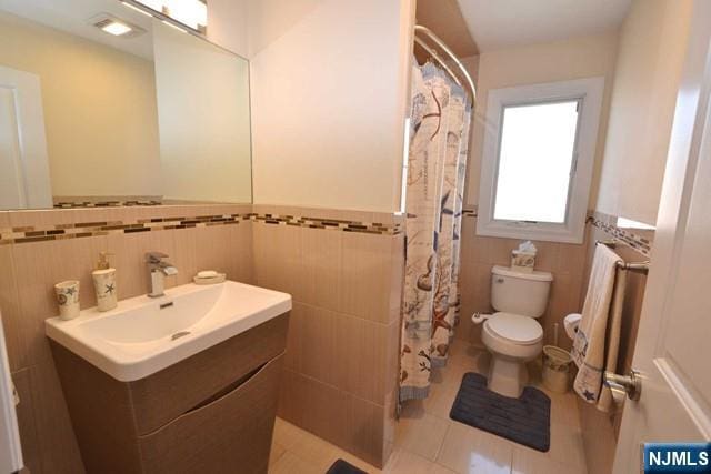 full bath featuring vanity, tile walls, toilet, and tile patterned floors