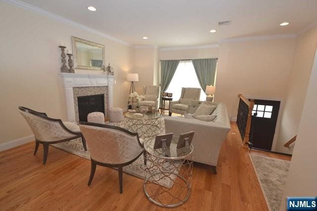 living area featuring ornamental molding, a fireplace, wood finished floors, and recessed lighting