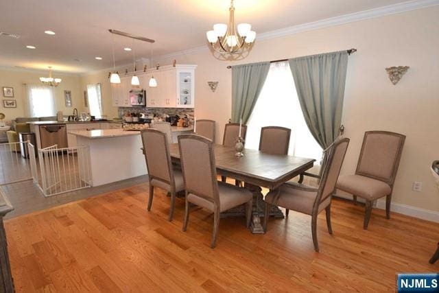 dining area with a notable chandelier, recessed lighting, ornamental molding, light wood-type flooring, and baseboards